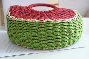 Primer plano de un bolso de paja artesanal con forma de sandía y detalles de tejido