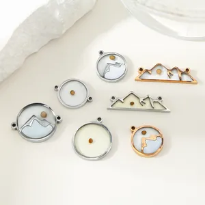 Detail view of mountain and circular stainless steel pendants containing real mustard seeds.