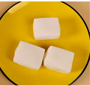 Drei realistische weiße Tofu-Squishy-Spielzeuge auf gelbem Teller zum Stressabbau