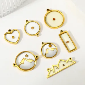 Close-up of golden stainless steel mustard seed pendants in heart and geometric shapes.