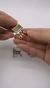 Main tenant un fermoir magnétique doré pour collier à plusieurs rangs avec crochets