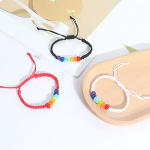 Detailed macro shot of three handmade braided rainbow knot bracelets on a wooden tray
