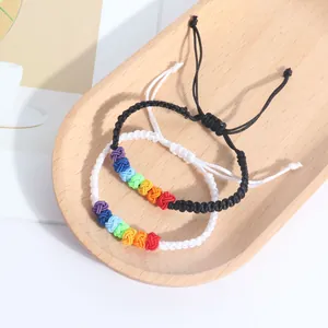 Close-up detail of two handmade rainbow knotted braided bracelets on a wooden tray