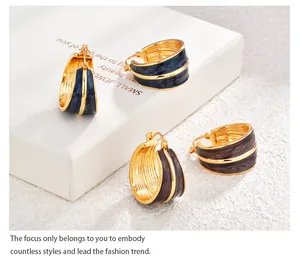 Dettaglio di orecchini a cerchio placcati oro con finitura smaltata blu e bordeaux