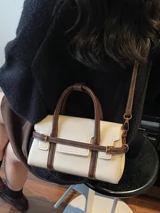 Elegant cream and brown minimalist leather handbag being worn as a shoulder bag.