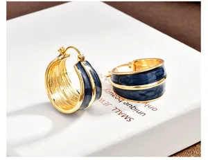 Primo piano di orecchini a cerchio vintage con bordo dorato e smalto blu navy a goccia