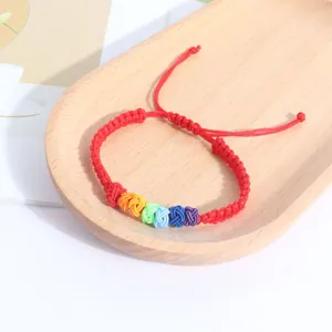 Close-up detail of a vibrant handmade rainbow braided rope bracelet on a wooden tray.
