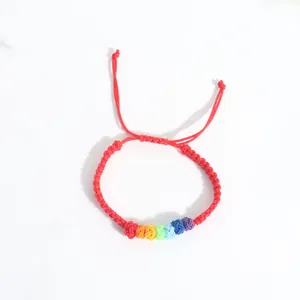 Macro view of handmade braided red string bracelet with colorful rainbow knot accents