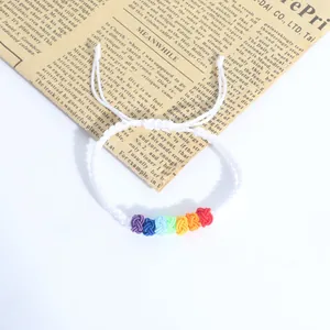 Macro view of a handmade white woven bracelet with seven colorful rainbow knots.