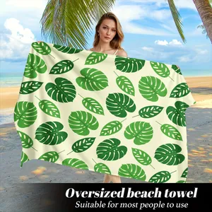 Vista dettagliata del telo mare oversize con motivi di foglie di Monstera verdi