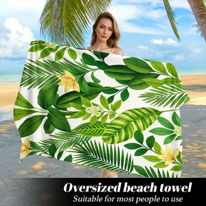 Dettaglio di un telo da mare oversize con stampe di foglie tropicali e fiori.