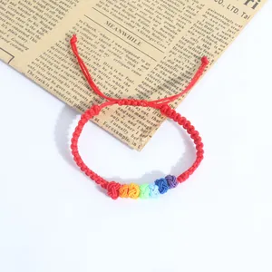 Detailed macro view of the vibrant rainbow knots on a handmade red woven bracelet