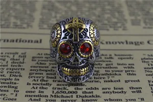 Gros plan d'une bague tête de mort gothique en acier inoxydable avec yeux en cristal rouge doré