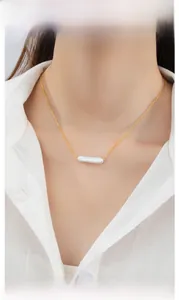 Detail view of a baroque pearl bar pendant necklace on a model's neck for elegant display.