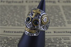 Vue détaillée d'une bague crâne punk en acier titane avec yeux en gemmes vertes et croix
