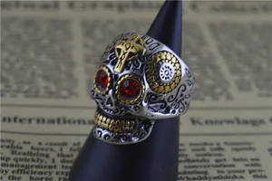 Gros plan d'une bague crâne punk en acier inoxydable avec yeux rouges et croix dorée