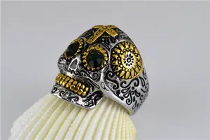 Vue détaillée d'une bague tête de mort en acier punk avec yeux verts et accents dorés