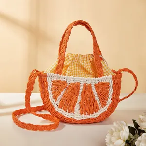 Dettaglio borsa in paglia a forma di arancia con fodera gialla e tracolla intrecciata.