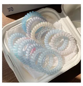 Gros plan d'élastiques à cheveux spirales multicolores dans un récipient blanc