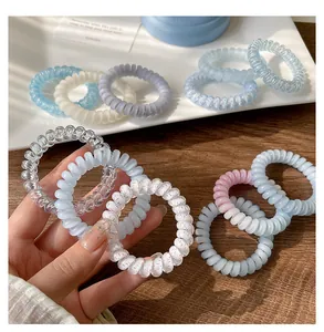 Gros plan de divers élastiques à cheveux en spirale pastel à haute élasticité tenus