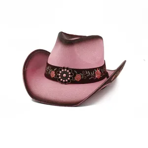 Detailed view of a pink straw cowboy hat featuring floral embroidery and a metal emblem