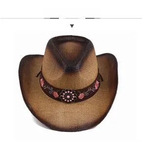 Detail view of brown straw cowboy hat with pink floral embroidery and metal buckle.
