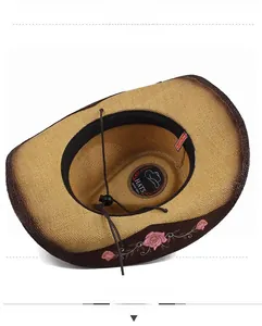 Detail of a straw cowboy hat with pink rose embroidery and adjustable strap.