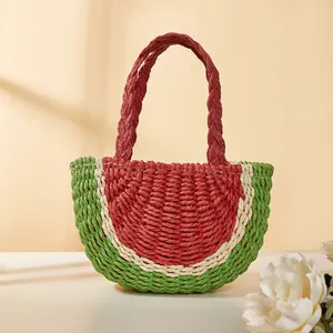 Dettaglio della borsa in paglia anguria intrecciata a mano con vivace trama rossa e verde.