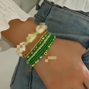 Close-up of Bohemian green seed bead and shell bracelet 7-piece set worn on a female wrist