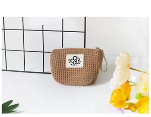 Close-up of a brown waffle fabric mini storage pouch featuring a cute black flower patch.