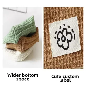 Close-up of waffle fabric storage pouch showing widened bottom and cute flower tag detail.