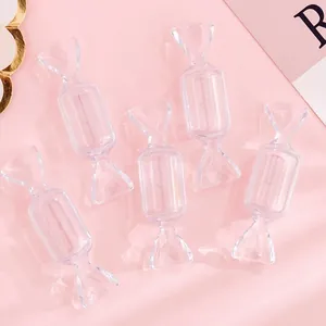 Mini scatole trasparenti a forma di caramella per piccoli gioielli su sfondo rosa