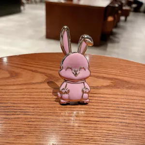 Primo piano di un supporto per telefono a forma di coniglio rosa su legno.