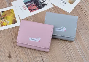 Top-down detail of minimalist pink and grey ladies' short wallets on a wood surface.