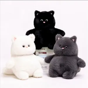 Three fluffy and adorable plush cat toys in black, white, and gray colors sitting on book props.
