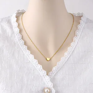 Close-up detail of a minimalist gold heart pendant on a thin stainless steel chain