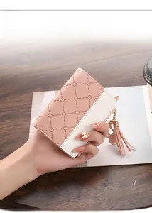 Detailed macro view of a slim pink quilted bifold wallet held in hand for size