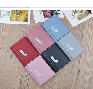 Colorful women's short foldable soft leather wallets arranged on a wooden background