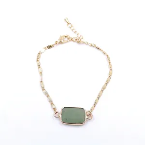 Close-up detail of an adjustable gold chain bracelet featuring a green square semi-precious stone