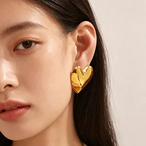 Detailed close-up view of a gold chunky heart stud earring worn by an Asian model