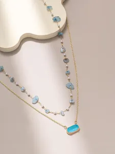 Dettaglio di collana a due strati in oro con gemma blu e pietre naturali preziose