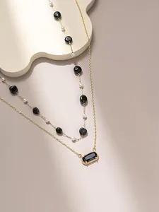 Primo piano di una collana a due strati placcata oro 18 carati con ciondolo nero