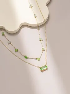 Dettaglio ravvicinato di collana a due strati dorata con pendente in gemma verde