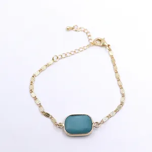 Detailed view of gold chain bracelet featuring a turquoise square stone centerpiece
