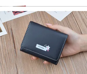 Detailed view of a minimalist black folded women's wallet with white floral print.