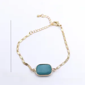 Close-up view of gold adjustable chain bracelet with rectangular turquoise stone.