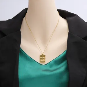 Detailed close-up of a gold stainless steel cross pendant necklace on a mannequin