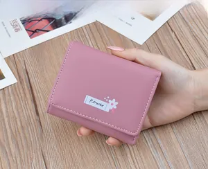 Close-up of a dusty pink soft leather foldable wallet being held in a woman's hand.