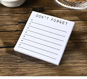 Detail eines weißen quadratischen Notizblocks mit dem Aufdruck 'Don't Forget' auf Holz.