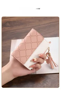 Close-up of pink and white quilted women's bifold wallet with tassel and swan charm.